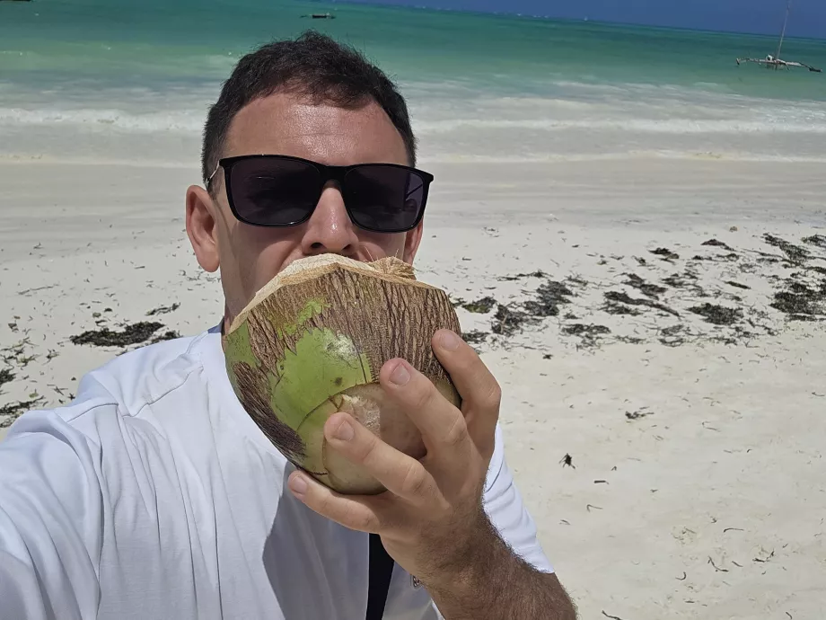 Jag dricker kokosnöt på stranden i Paje